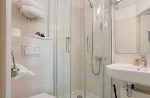 a bathroom with a shower and a sink at Brit Hotel Reims La Pompelle in Reims