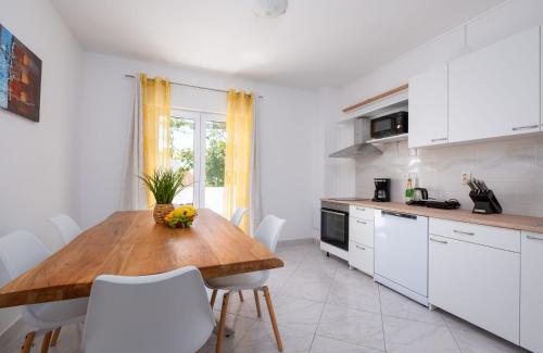 a kitchen with a wooden table and white cabinets at Lucky Bay - Comfort & Terrace Vibes in Mlini