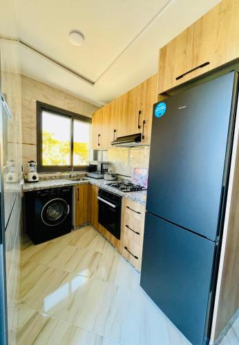 a kitchen with a black refrigerator and wooden cabinets at إقامة القدس in Riffiene