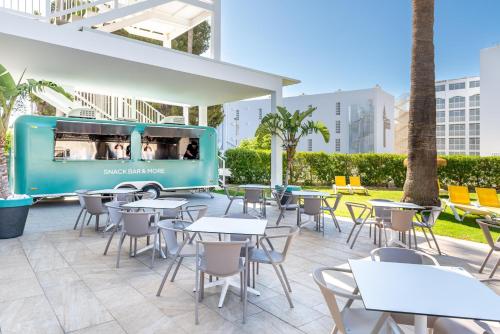 an outdoor patio with tables and chairs and a food truck at THB San Fermín in Benalmádena