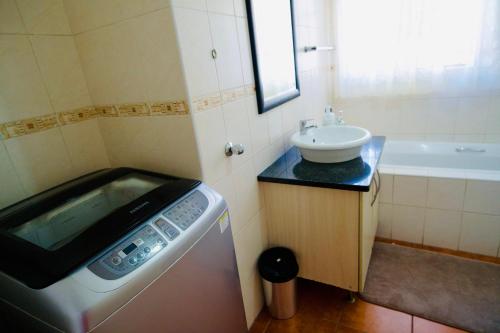 a small bathroom with a washing machine and a sink at Palm Haven 5 min drive to Carlswald Centre in Midrand