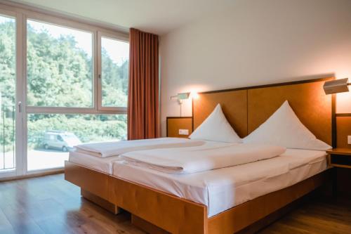 a bedroom with a large bed with a large window at Hotel Hegau OST in Engen
