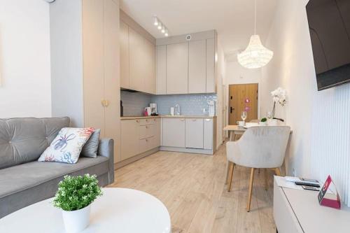 a living room and kitchen with a couch and a table at VacationClub - Moon Residence Apartament 14 in Ustronie Morskie