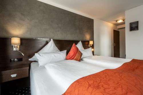 a bedroom with two beds with white sheets and red pillows at Hotel Ochsen in Bad Saulgau