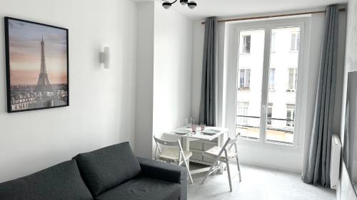 un salon avec un canapé, une table et une fenêtre dans l'établissement 117- Charmant Appartement Cosy pour 5 au Cœur de Paris, à Paris