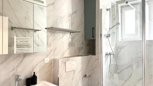 une salle de bain blanche avec une douche et un lavabo dans l'établissement 117- Charmant Appartement Cosy pour 5 au Cœur de Paris, à Paris