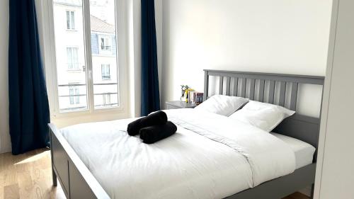 un lit avec un ours en peluche noir assis sur lui dans l'établissement 117- Charmant Appartement Cosy pour 5 au Cœur de Paris, à Paris