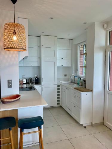 une cuisine avec des placards blancs et une lampe pendant dans l'établissement Villa vue mer panoramique en Baie de somme, à Ault