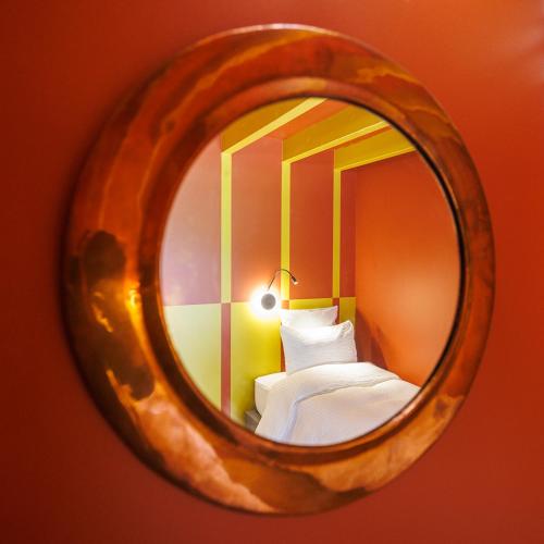 un miroir reflétant une chambre avec un lit et une lampe dans l'établissement Moulin de Retord, côté étang - Chambres d'hôtes, à Pérassay