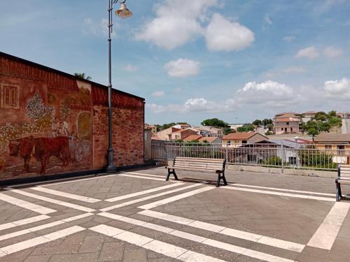 two benches sitting next to a brick wall with a mural at La casetta by Holiday World in Olmedo