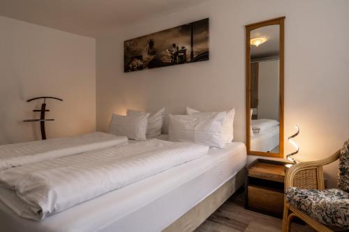 a white bedroom with two beds and a mirror at Hotel Ochsen in Bad Saulgau