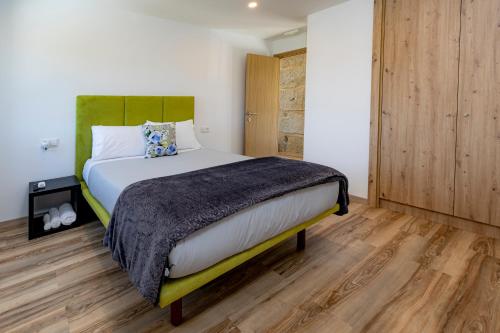 a bedroom with a large bed and wooden floors at Cruzeiros Guest House, piscina, jacuzi, grupos in Tangil