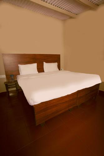 a bedroom with a large bed with white sheets at REFLECTIONS Guest House in Ooty