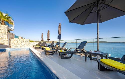ein Pool mit Stühlen und einem Sonnenschirm neben dem Wasser in der Unterkunft Beautiful Home In Sevid in Sevid