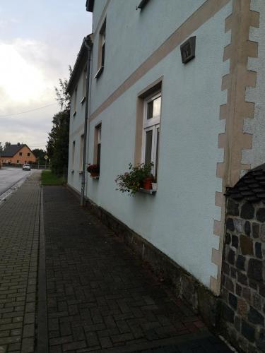 een wit gebouw met bloemen in een raam bij Ferienwohnung in Brandis