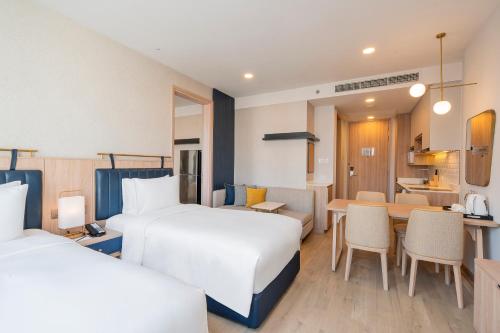 a hotel room with two beds and a dining room at Staybridge Suites Bangkok Thonglor by IHG in Bangkok