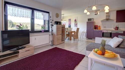sala de estar con TV y mesa con un bol de fruta en Ferienwohnung Seeblick I, en Schalkenmehren