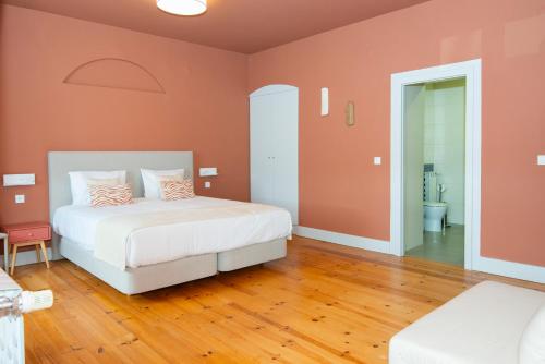 a bedroom with a bed with orange walls and wooden floors at Palácio dos Marqueses in Mafra