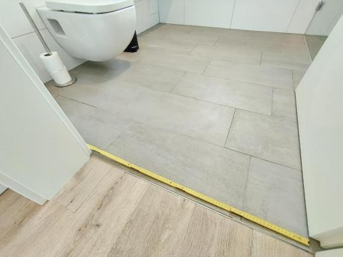 a yellow hose on a bathroom floor with a toilet at CityVibe Apartment für bis zu 4 in Erlangen
