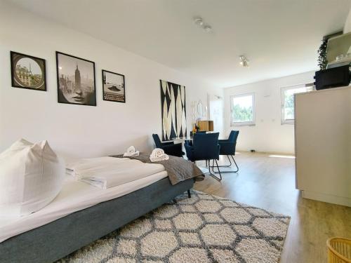 a bedroom with a bed and a living room with chairs at CityVibe Apartment für bis zu 4 in Erlangen