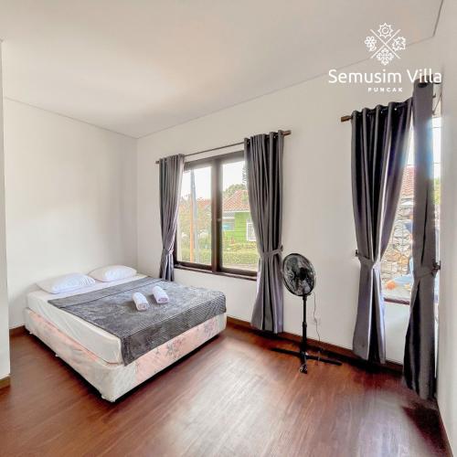 a bedroom with a bed and a large window at Sierra by Semusim Villa in Cianjur