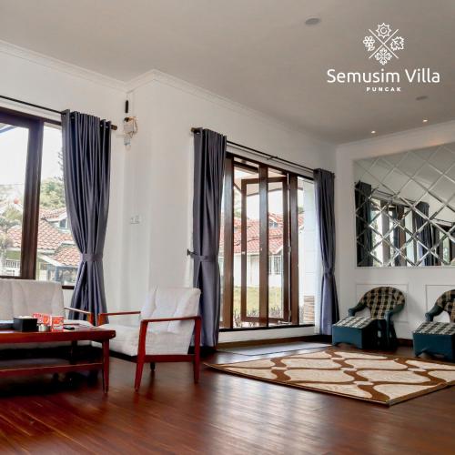 a living room with white walls and blue curtains at Sierra by Semusim Villa in Cianjur