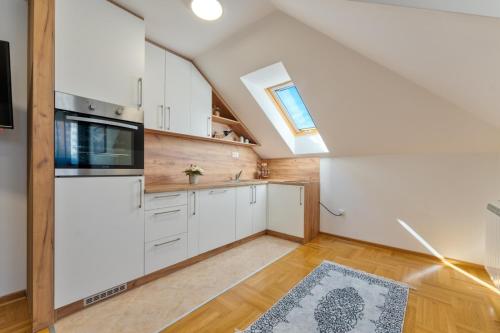 an attic kitchen with white cabinets and a window at CENTRUM APARTMENT Zlatibor in Zlatibor