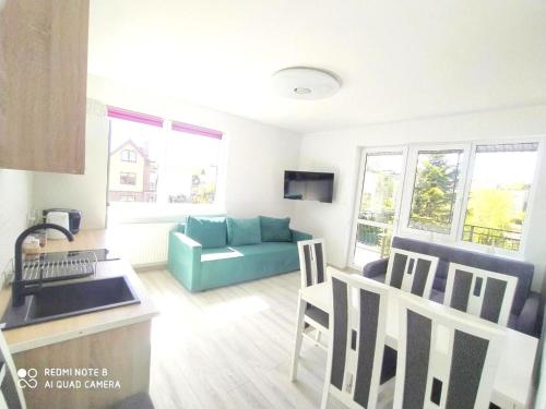 a living room with a blue couch and a kitchen at Willa Loka Apartamenty in Władysławowo