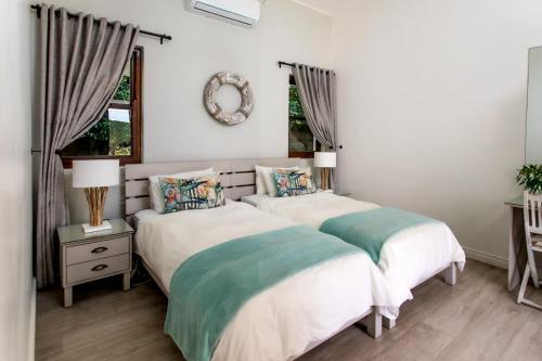 two beds in a white room with a mirror at Sixteen Guesthouse on Main in Hermanus