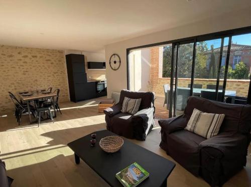 un salon avec des canapés et une table ainsi qu'une salle à manger dans l'établissement L'ancienne grange du village d'Alenya, à Alénya
