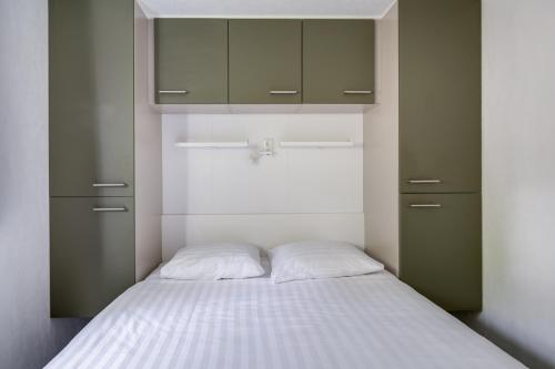 a bedroom with a bed with white sheets and cabinets at Heerlijk huisje op de Veluwe in Hoenderloo