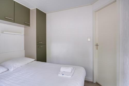 a bedroom with two beds with white sheets and towels at Heerlijk huisje op de Veluwe in Hoenderloo
