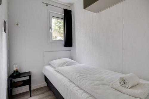 a white bedroom with a bed and a window at Heerlijk huisje op de Veluwe in Hoenderloo