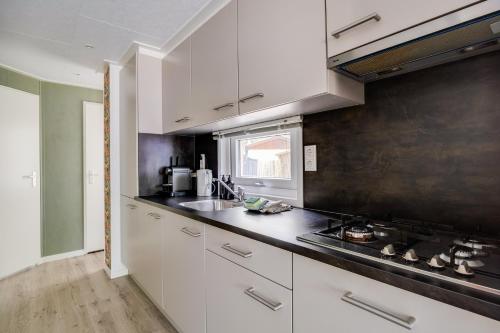 a kitchen with white cabinets and a black counter top at Heerlijk huisje op de Veluwe in Hoenderloo