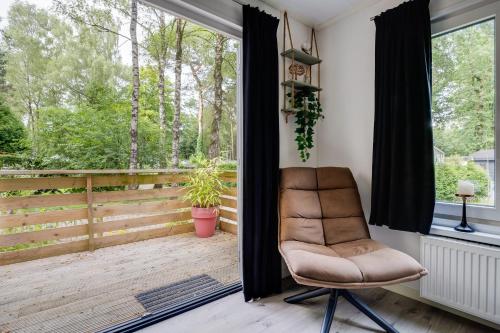 a chair sitting on a porch with a large window at Heerlijk huisje op de Veluwe in Hoenderloo
