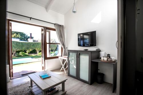 a living room with a tv and a table with a coffee table at Sixteen Guesthouse on Main in Hermanus