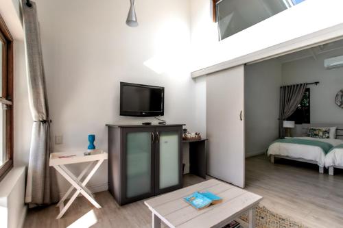 a living room with a tv and a bed at Sixteen Guesthouse on Main in Hermanus