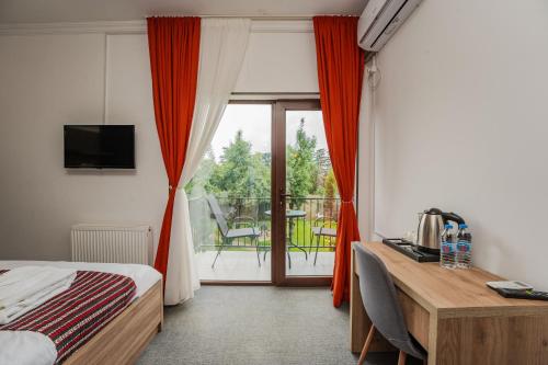 a bedroom with a bed and a desk and a balcony at Vineyard Hotel & Winery in Napareuli