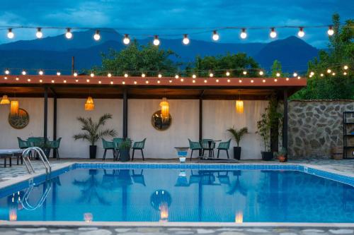 a pool with lights and a patio with a table and chairs at Vineyard Hotel & Winery in Napareuli