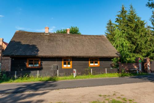 an old house with a thatched roof on a street at Agroturystyka Hanka i Jurek in Boruja