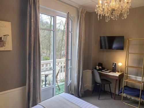 a bedroom with a bed and a desk and a window at BRIT HOTEL & SPA Le Roc au Chien in Bagnoles de l'Orne