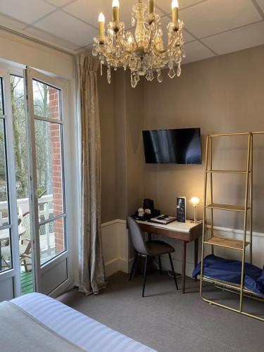 a bedroom with a desk and a bed and a chandelier at BRIT HOTEL & SPA Le Roc au Chien in Bagnoles de l'Orne