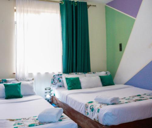 a room with two beds and a window at Hirwado Homes & Cozy Rooms JKIA -3 Bedrooms With 5beds, 2Baths in Nairobi