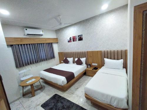 a hotel room with two beds and a window at Hotel Lee Pride in Anand