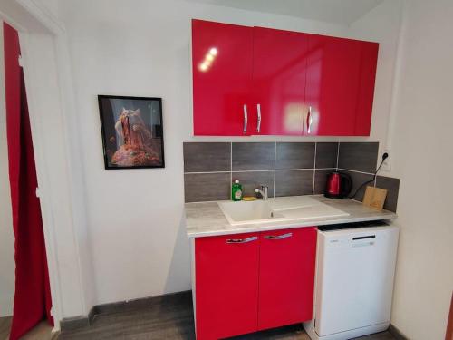 - une cuisine rouge avec un évier et des placards rouges dans l'établissement Le Surréaliste près de Nancy, à Varangéville