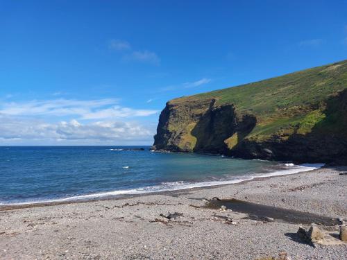 a beach with a rocky shore and the ocean at Alphi 4 in Bude