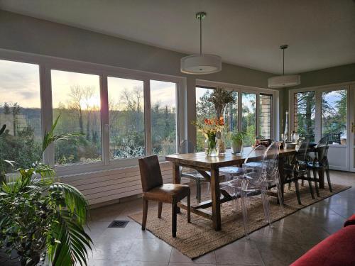 une salle à manger avec une table, des chaises et des fenêtres dans l'établissement La petite galerie, à Bagneaux-sur-Loing