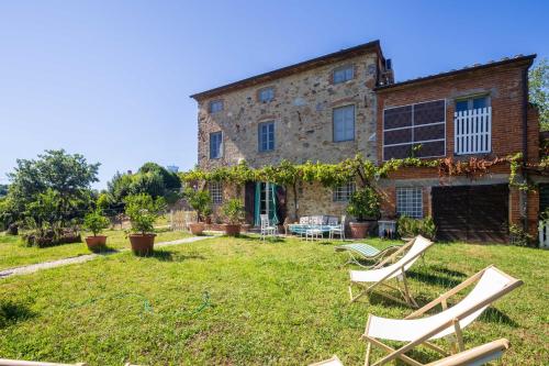 an old stone house with chairs in the yard at Villa Isabò by VacaVilla in Capannori
