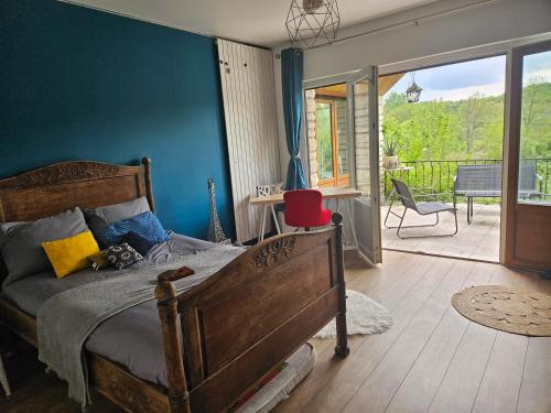 Cette chambre comprend un lit avec un mur bleu et un balcon. dans l'établissement La petite galerie, à Bagneaux-sur-Loing