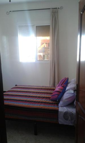 a bed in a room with a window and pillows at Mirleft Trip in Mirleft